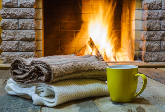 Tasse pour le thé ou le café, choses de laine près de la cheminée, maison de campagne, vacances d&#39;hiver