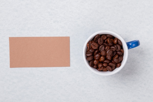 Tasse remplie de grains de café et de papier vierge pour copyspace