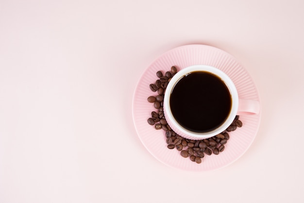 Tasse rose de café noir sur fond rose pastel, monochrome, vue de dessus