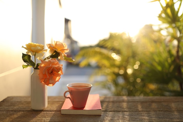 Tasse rose pastel avec fleur rose et livres à l'extérieur