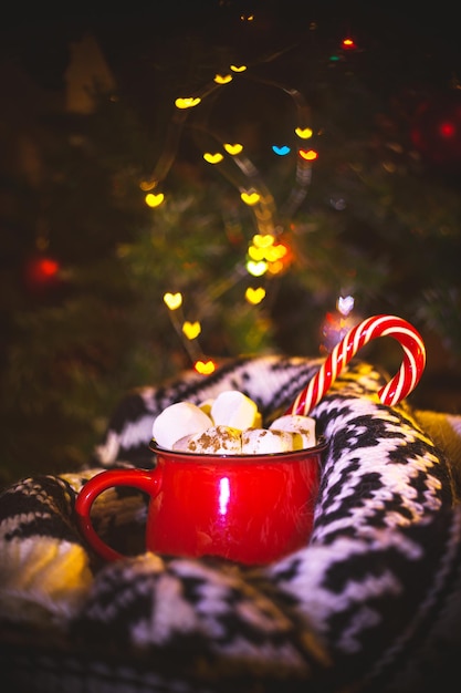 Tasse rouge avec du cacao et des guimauves. Décorations de Noël traditionnelles.