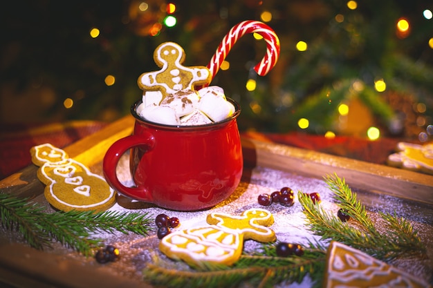 Tasse rouge avec du cacao et des guimauves. Pain d'épice maison. Décorations de Noël traditionnelles.