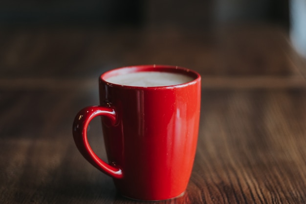 Tasse rouge avec du café mokachino dans un café sur fond sombre