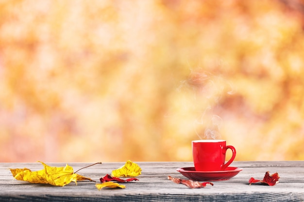 Tasse rouge et feuilles d'automne sur la table