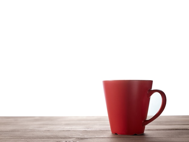 Tasse rouge sur table en bois avec fond isolé