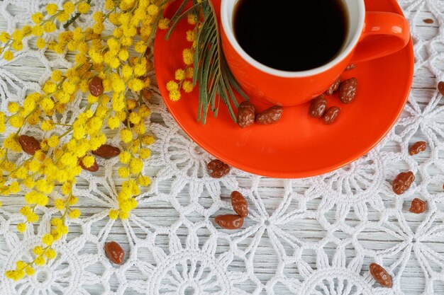 Tasse et soucoupe décorées d'un mimosa et de bonbons sur une belle nappe au crochet