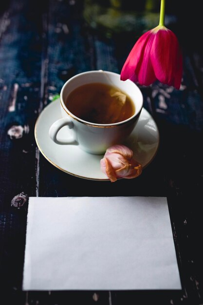 Tasse en T sur fond de bois avec tulipes printanières et feuille blanche et esprit