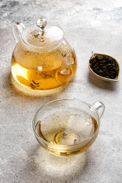 Une tasse ou une tasse avec une tisane verte et une théière avec des feuilles de thé sur fond gris. Couleur beauté