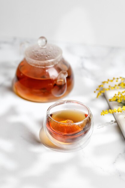 Une tasse ou une tasse en verre avec une tisane et une théière en journée ensoleillée printemps été