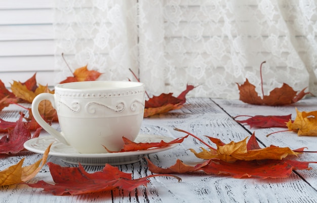 Tasse de thé anglais avec du lait sur un tableau blanc avec des feuilles d'érable