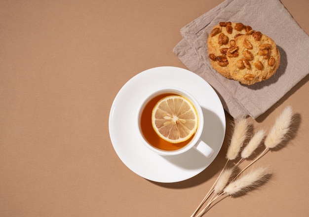 Une tasse de thé au citron et des biscuits faits maison sur une serviette sur fond marron concept de boisson saine et confortable vue de dessus et espace de copie