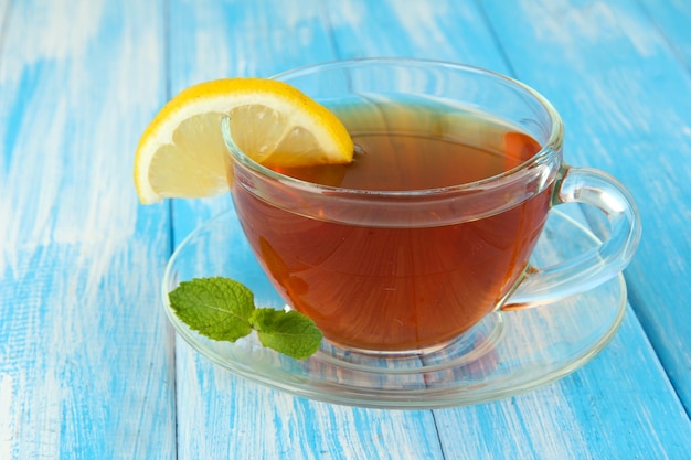 Tasse de thé au citron sur table sur fond bleu