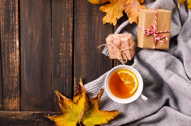 Tasse de thé au citron sur une table sombre en bois avec des feuilles d'automne