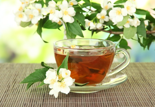 Tasse de thé au jasmin sur natte de bambou sur fond clair