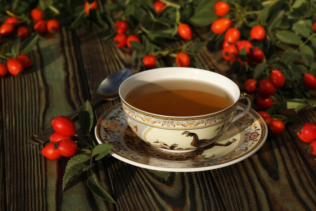 Tasse de thé aux baies de rose sur un fond en bois