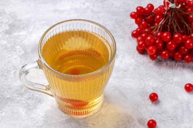 Une tasse de thé avec des baies de sorbier rouge sur une table lumineuse