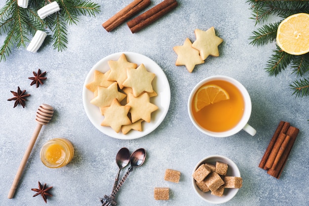 Tasse de thé et biscuits, branches de pin, bâtons de cannelle, étoiles d'anis