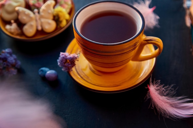 Tasse à thé et biscuits faits maison à l'esthétique de Pâques avec des décorations Heure du thé des aliments de vacances sur fond noir