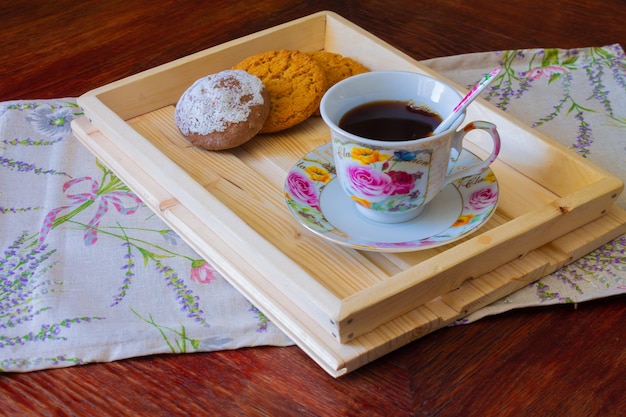 Une tasse de thé avec des biscuits sur un plateau en bois