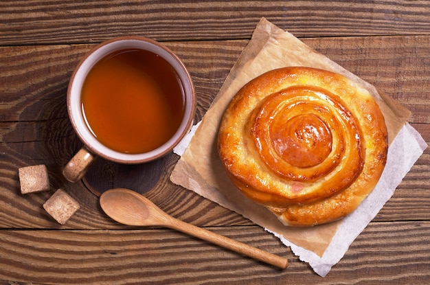 Tasse de thé et brioche sucrée sur la vieille vue de dessus de table en bois