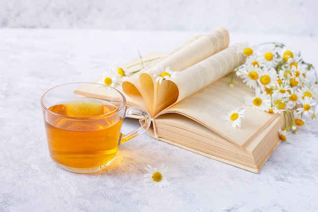 une tasse de thé à la camomille et un bouquet de marguerites dans un vase