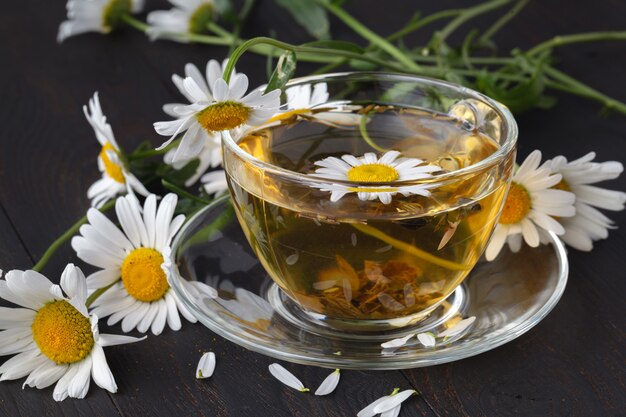 Tasse de thé à la camomille avec des fleurs de camomille sur des planches en bois