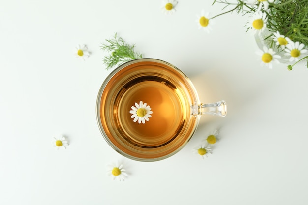 Tasse de thé à la camomille et ingrédients sur blanc