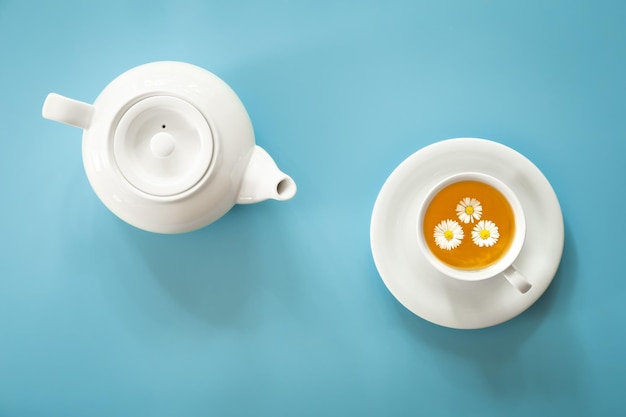 Une tasse de thé à la camomille et une théière sur fond bleu