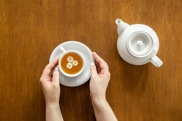 Une tasse de thé à la camomille et une théière sur un fond en bois