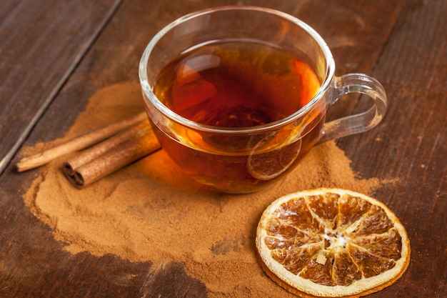 Tasse de thé à la cannelle chaude aromatique sur une table en bois