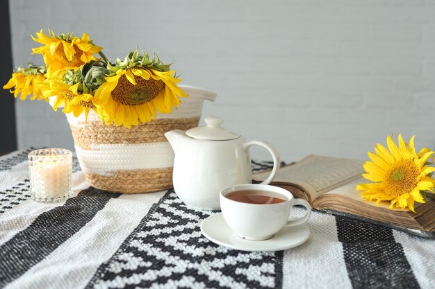 Une tasse de thé à la cannelle sur un plateau en bois et un livre vintage ouvert à l'esthétique des tournesols