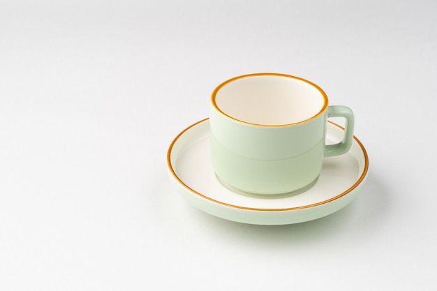 Une tasse à thé en céramique blanche et vert pastel aux contours orange