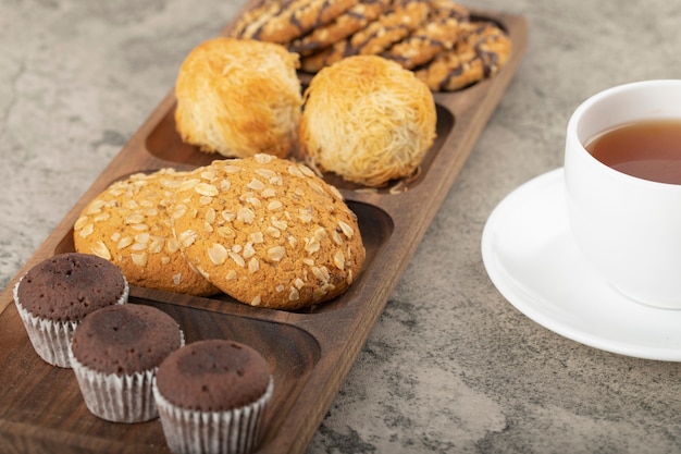 Tasse de thé chaud avec assiette de divers bonbons sur la table.