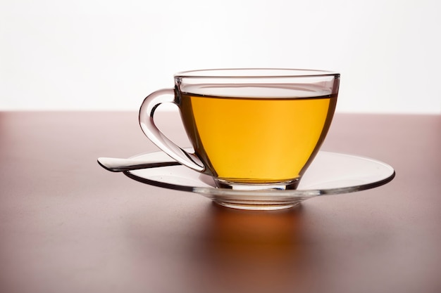 Une tasse de thé chaud fraîchement infusé dans un verre sur la table.