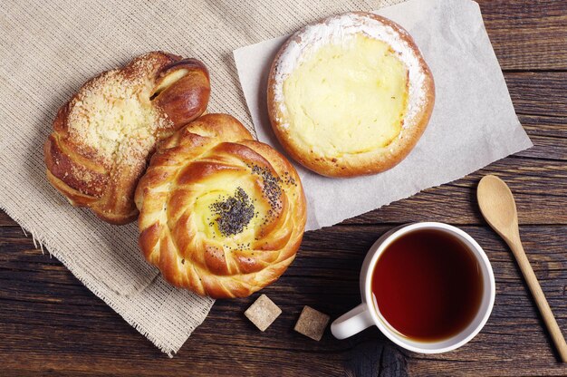 Tasse de thé chaud et petits pains frais sur une vieille table en bois, vue de dessus