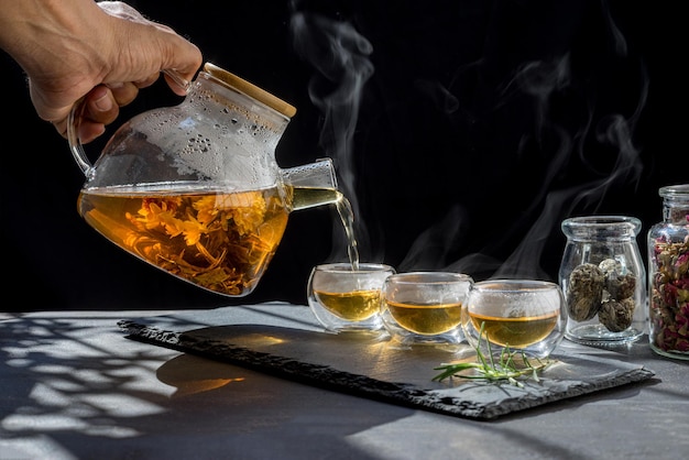 Photo tasse de thé chaud sucre de canne feuilles de thé sèches, thé chaud dans une tasse en verre avec de la vapeur et du citron. nourriture chaude et concept de repas sain