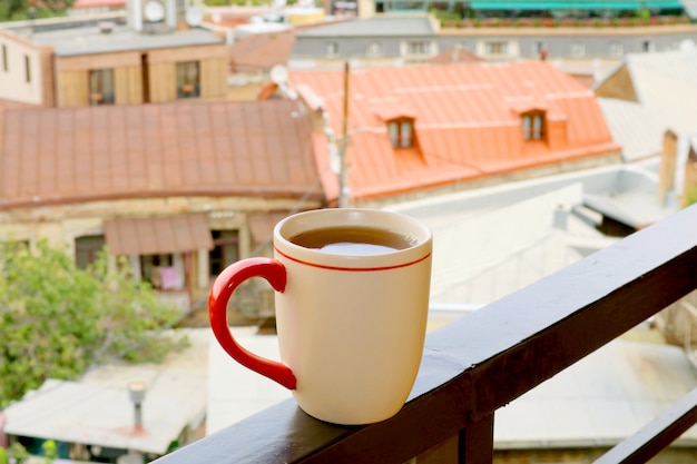 Tasse de thé chaud sur la terrasse avec vue floue sur la ville en toile de fond