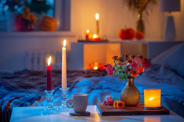 Tasse de thé et de chrysanthème dans un vase avec des bougies allumées dans la chambre