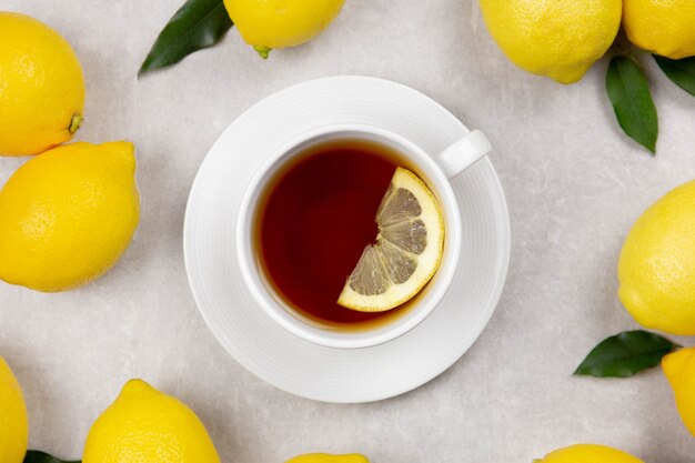 Tasse de thé avec des citrons frais et des feuilles sur la surface de la pierre en béton blanc