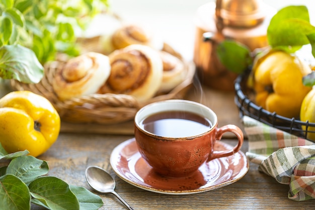 Tasse de thé avec de la confiture de coing maison sur un vieux fond en bois. Fruits frais et feuilles de coing sur le fond. Photo horizontale. rustique