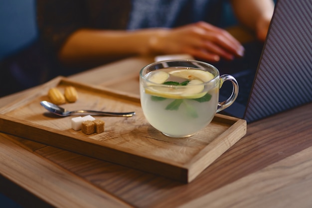 Tasse de thé confortable, encore vie, biscuits sur le fond d&#39;une fille derrière un ordinateur portable