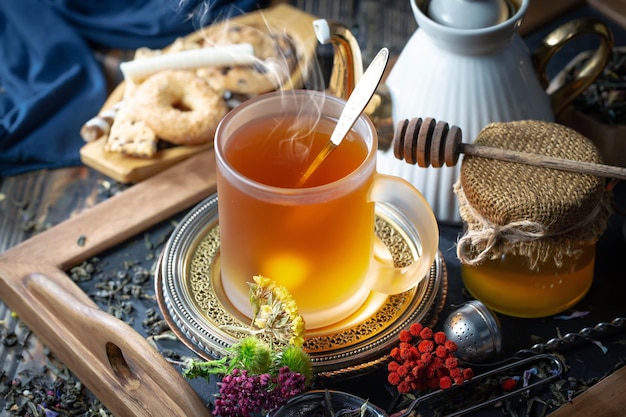 Une tasse de thé avec une cuillère et un sac de miel sur une table.