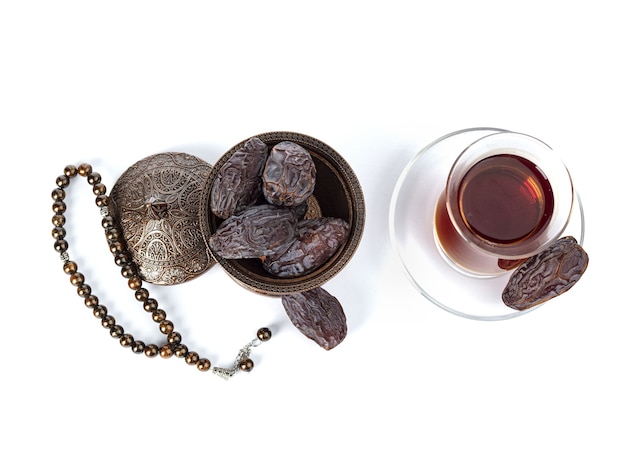 Une tasse de thé avec des dates sur une assiette isolée