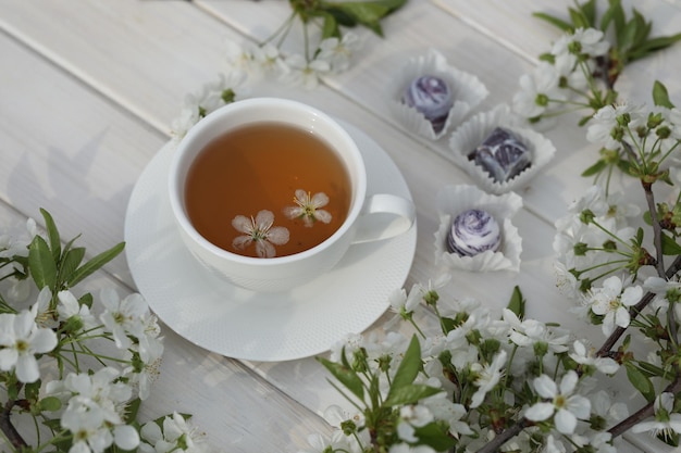 tasse de thé avec décoration de fleurs de cerisier sur fond de bois blanc