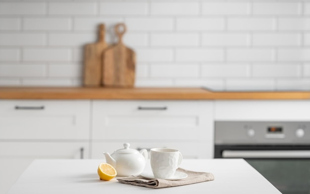 Photo une tasse de thé avec du citron et une théière sur une table blanche