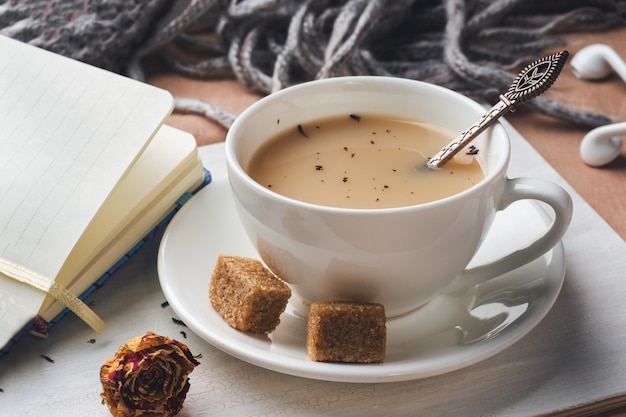 Tasse de thé avec du lait, du sucre d&#39;anis brun et un bloc-notes. Plateau sur le couvre-lit. ton vintage. Concept de style de vie.