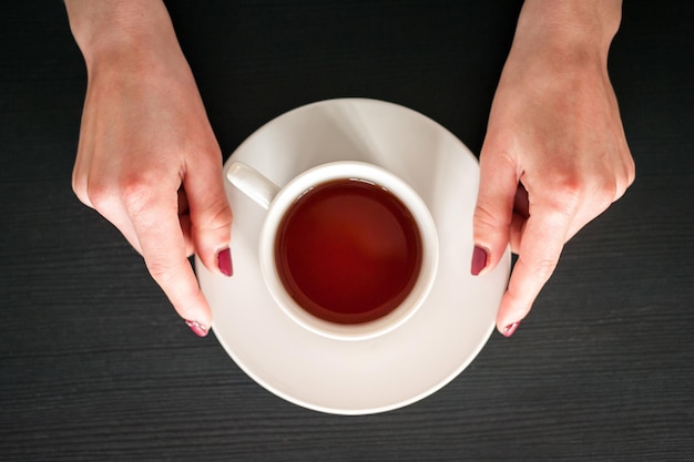 Tasse de thé du matin entre les mains d'une jeune femme