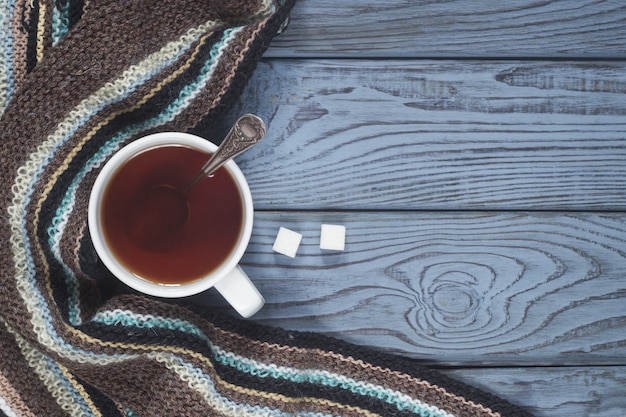 Une tasse de thé et une écharpe tricotée sur fond de table en bois bleu