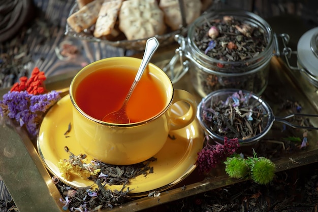Une tasse de thé est posée sur une assiette à côté de quelques feuilles de thé.
