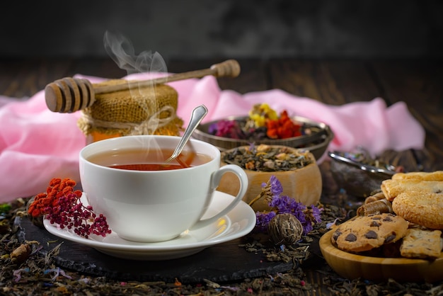 Une tasse de thé est posée sur une table avec divers biscuits et autres thés.